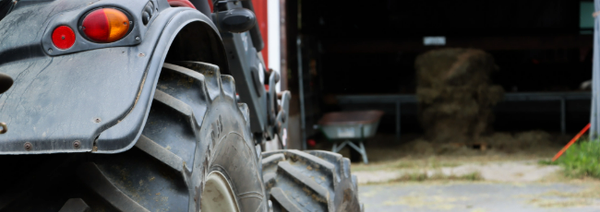 Traktori kuvattuna takaapäin. Taustalla näkyy siilossa oleva kottikärry ja heinäkasoja