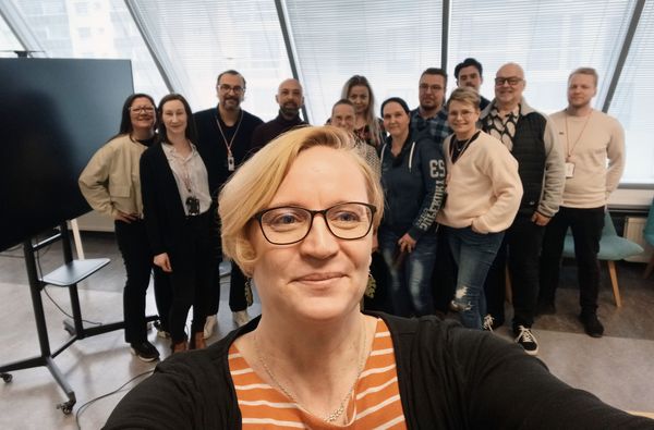 Ryhmä hymyileviä ihmisiä toimistotilassa.