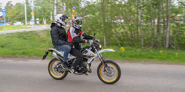 Kaksi nuorta mopon selässä.