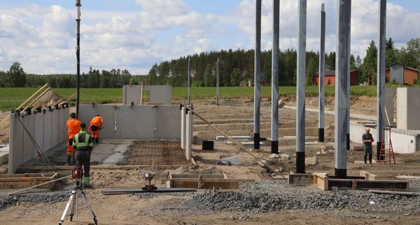 Ison rakennuksen perustuksia valetaan maalaismaisemassa.