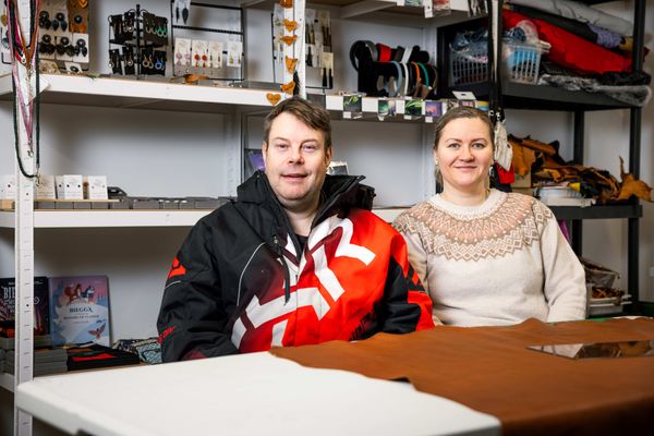 Pariskunta istuu vierekkäin ja hymyilee.