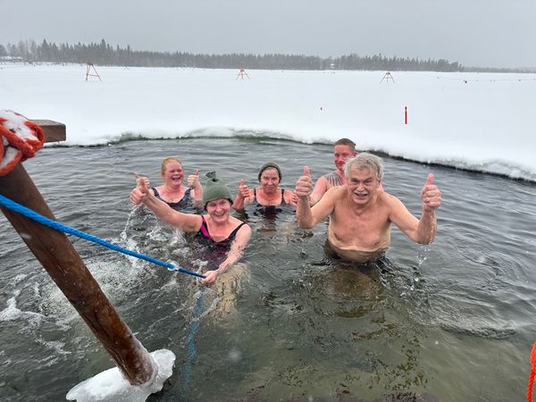 Ihmisiä avannossa peukut pystyssä.