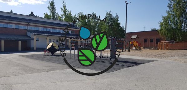 Kuvssa koulun piha, jossa on asfalttia ja muutama leikkiteline