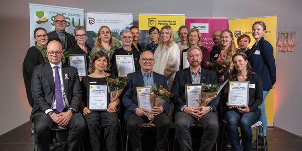 ihmisiä istumassa ja poseeraamassa palkintojen kanssa