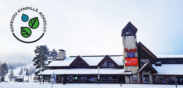 Piirretty kaupunkimaisema, jossa tie, bussi, aikuinen ja lapsi, rakennuksia, pyöräilijä