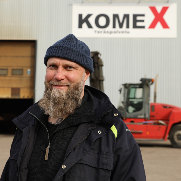 Mies hallin edessä, jonka seinässä lukee Komex