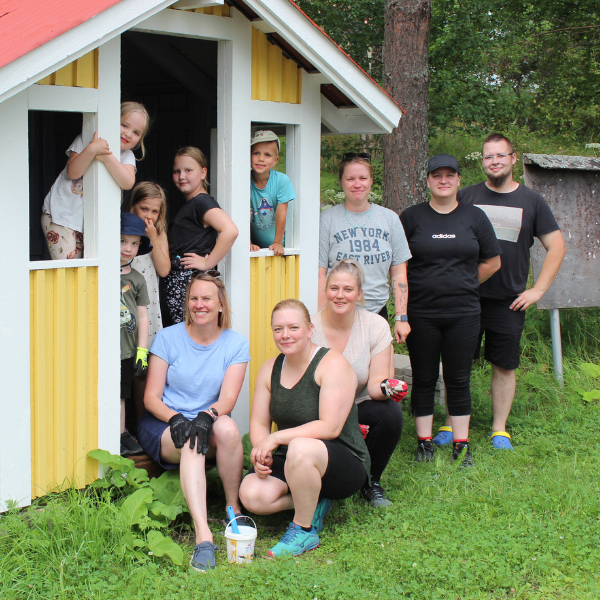 Lapsia ja vanhempia keltaisen rakennuksen ovensuussa kesällä.
