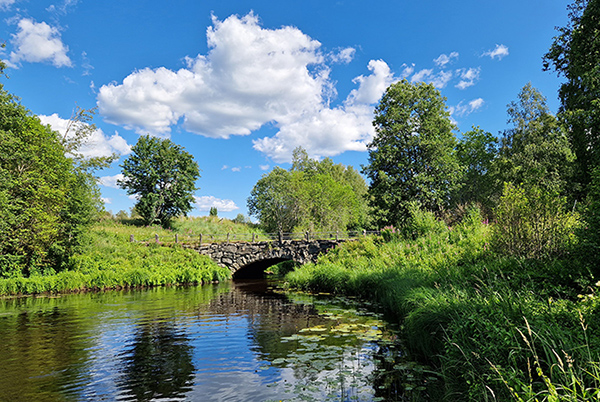 Kivinen silta, vettä, vehreää luontoa.