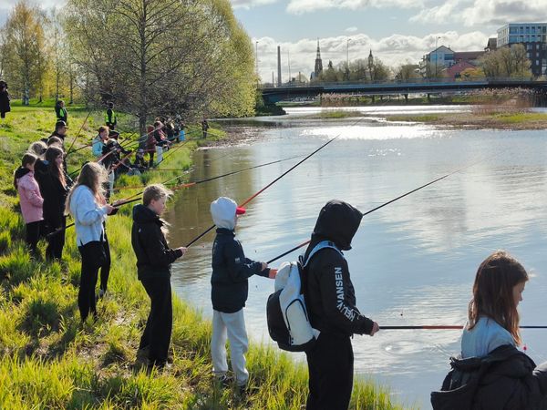 Koululaiset onkimassa jokirannassa.