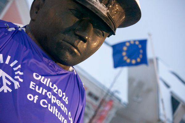 Kuvassa EU-lippu ja Oulun Toripoliisi patsas. Oulu2026. European City of Culture.