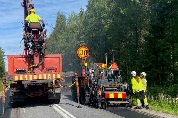 Työkoneita ja työntekijöitä asfalttityömaalla.