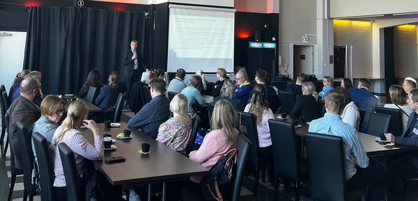 Kuvassa Kaakkois-Suomen tiiminvetäjä Samuli Leveälahti pitää esitystä, ja yleisö kuuntelee