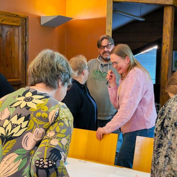 Eri-ikäisiä lappilaisia pöydän ympärillä hyväntuulisina.