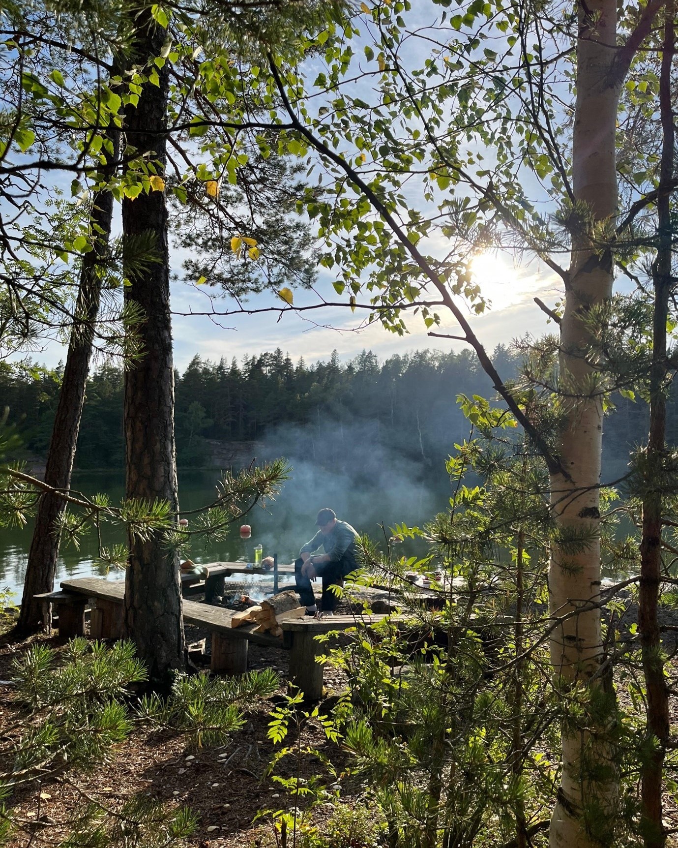 Henkilö rannalla olevalla nuotiopaikalla.