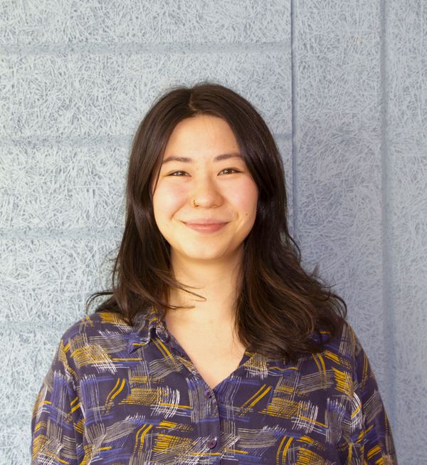 Taina Huusko-Leinonen katsoo kameraan, valkoinen tausta.