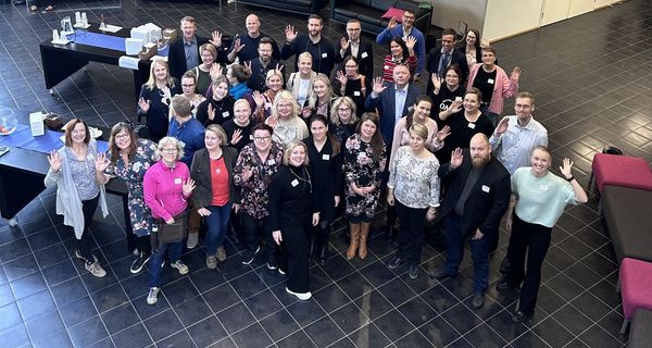 kuva joukosta ihmisiä yläviistosta otettuna, ihmiset vilkuttavat kameralle