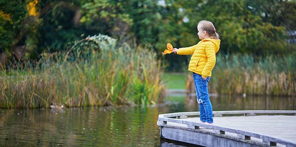 Tyttö laiturilla lammen reunalla syksyllä.