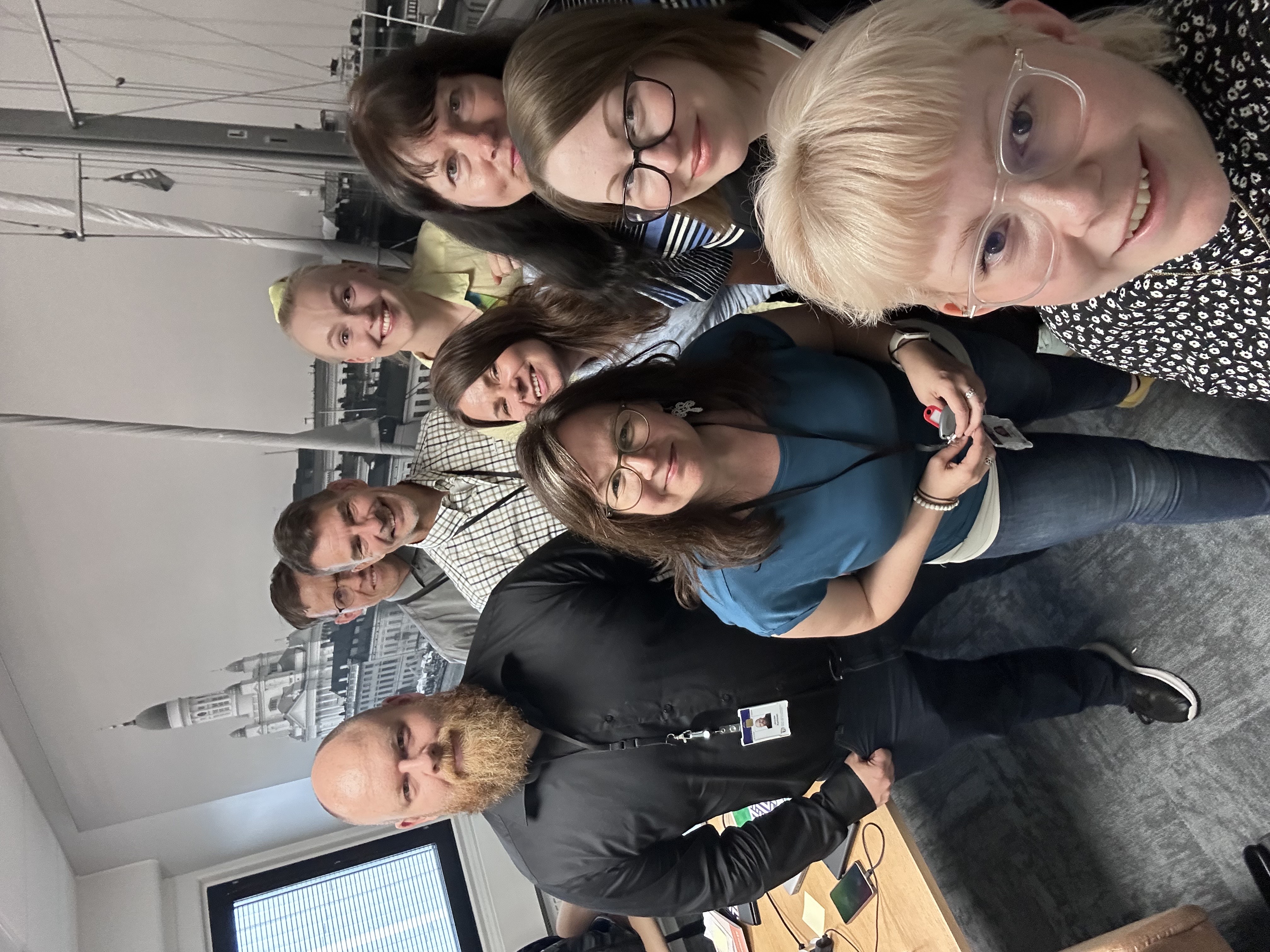 kuva tiimistä, yhdeksän henkilöä katsoo kameraan toimistotilassa