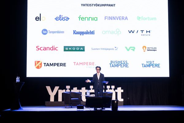 juontaja lavalla, takana logoja.