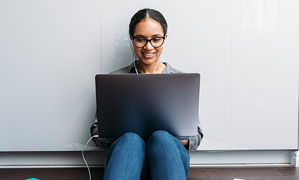 Nainen istuu tietokone sylissä.