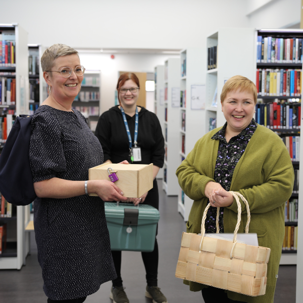 Iloiset ihmiset pitävät oppimispakettja käsissään. Paketit ovat reppu, kori ja salkku.